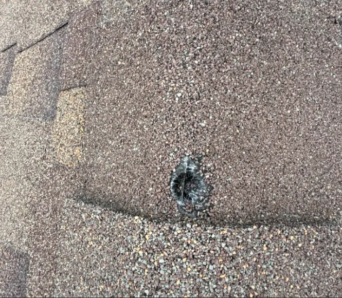 Circular roof vent with cracked flashing and tar on a brown pebble-like shingle roof (indicating possible leak).id